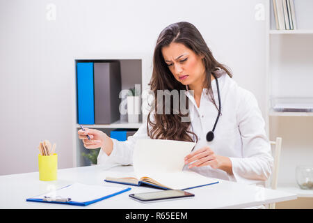 Angry female doctor looking at documents while working at her office. Stock Photo