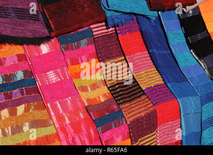 Morocco. Typical colourful hand crafted silk cloth covers on display in a Medina souk. Stock Photo