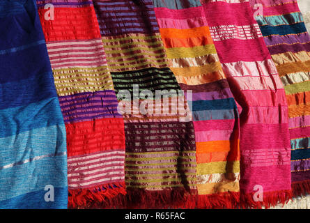 Morocco. Typical colourful hand crafted silk cloth covers on display in a Medina souk. Stock Photo
