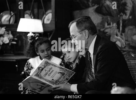President George H. W. Bush in the Diplomatic Reception Room of the White House, reading a book to children gathered around him as part of Great American Read Aloud Day on April 16, 1991. Stock Photo