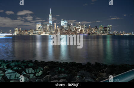 Buildings are illuminated at night looking across the upper bay and Hudson River to the borough of Manhattan Stock Photo