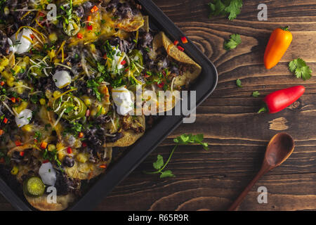 Top view baked pan of nachos with beef, cheese, black beans, peppers, jalapenos Stock Photo