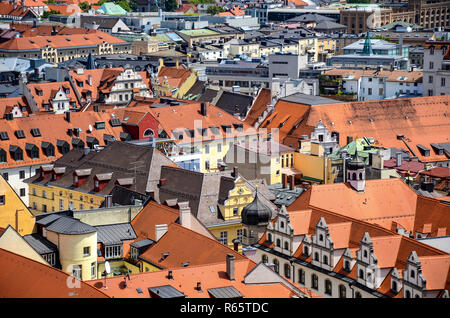 Dense urban cityscape of red rooftops and colorful buildings in yellow, white, and green colors in the city center of Munich, Germany Stock Photo