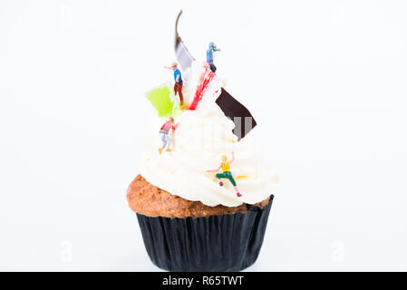 Concept of sugar high or sugar rush with miniature people going up the frosting of cupcake Stock Photo