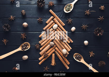 Christmas tree made of cinnamon, star anise, spices and nutmeg on dark background Stock Photo