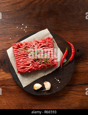Minced beef meat with salt, garlic, herbs on wooden table. Top view. Stock Photo