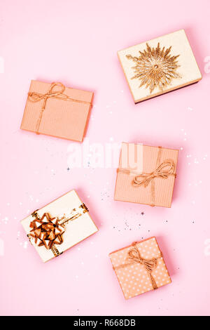 Five Christmas craft gift boxes with glitter on pink pastel background. Flat lay style. Festive concept. Stock Photo