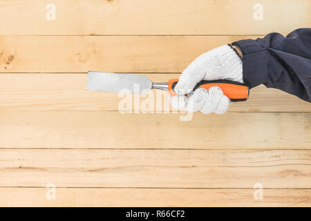 Hand in glove holding chisel Stock Photo