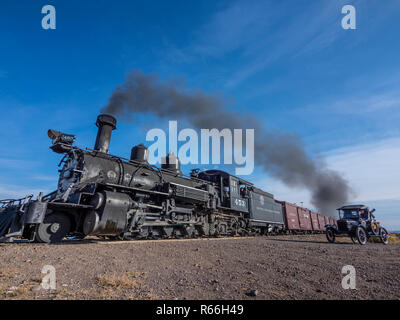 Locomotive 453 steam-engine freight train approaches County Road E5 crossing with a Model-T waiting by the tracks. Stock Photo