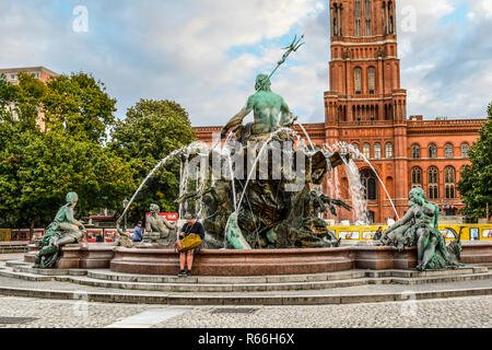 Tourists relax at the Neptune Fountain in the courtyard in front of the Rotes Rathaus or Red Town Hall in Alexanderplatz in Berlin, Germany Stock Photo