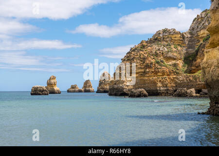 High cliffs, rock formations, blue sky, and the calm aqua blue waters of the Atlantic Ocean on Portugal's Algarve coast Stock Photo