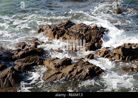 Sea waves splashing on the stone reef off the coast Stock Photo