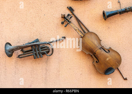 Retro style musical instruments hanging from a wall, a musical vintage view of a violin and an old trumpet transporting us around history to old times Stock Photo