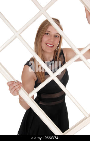 https://l450v.alamy.com/450v/r66w74/a-beautiful-blond-woman-holding-up-a-white-window-frame-and-looking-trough-smiling-in-a-black-dress-isolated-for-white-background-r66w74.jpg
