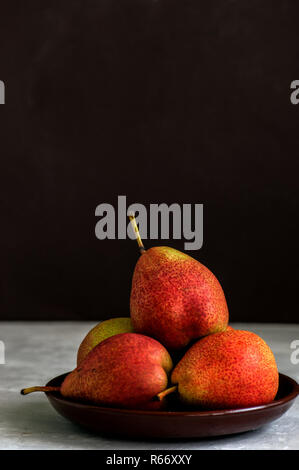 Group of ripe pears in a plate on a white stone background. Clos Stock Photo