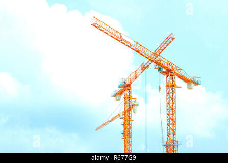 Two orange crane in cross on blue sky Stock Photo