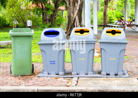 Four bins are on the sidewalk in the park. Stock Photo