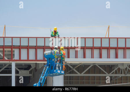 Workers in a baskets are installing sheet, building a factory. Stock Photo