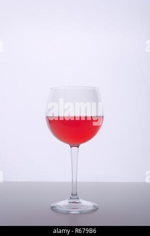 a glass with a red drink on a white surface Stock Photo