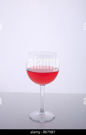 a glass with a red drink on a white surface Stock Photo