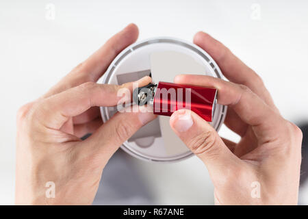 Person's Hand Inserting Battery In Smoke Detector Stock Photo