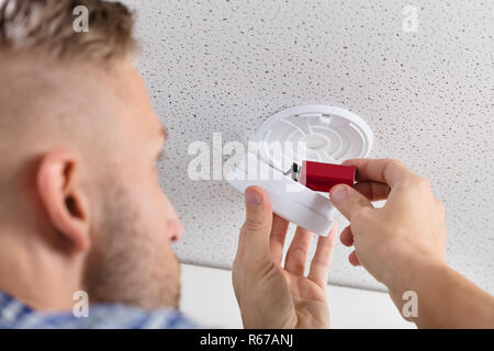 Person's Hand Inserting Battery In Smoke Detector Stock Photo