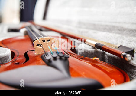 brown vintage violin with bow lying in a case closeup indoor Stock Photo
