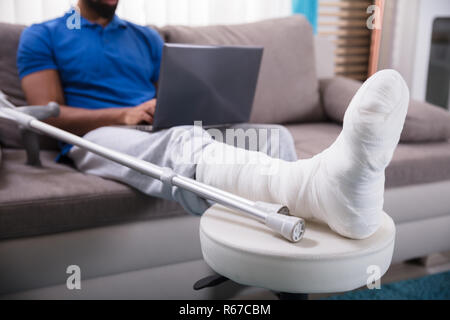 Man With Broken Leg Using Laptop Stock Photo