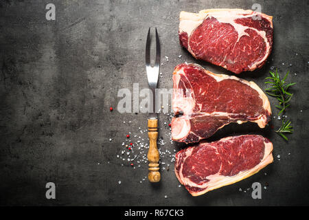 Dry aged beef steaks - ribeye, striploin, t-bone steaks on Black Stock Photo