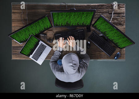 Hacker Hacking Multiple Computers On Desk Stock Photo