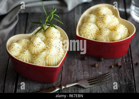 Shepherd's pie in small individual heart shape red ramikens, traditional British dish with minced meat and mashed potato on rustic wooden table Stock Photo