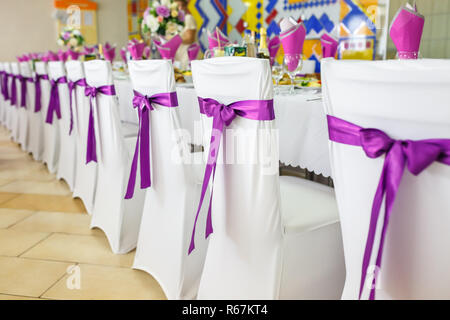 Beautiful flowers on elegant dinner table in wedding day. Decorations served on the festive table in violet background Stock Photo