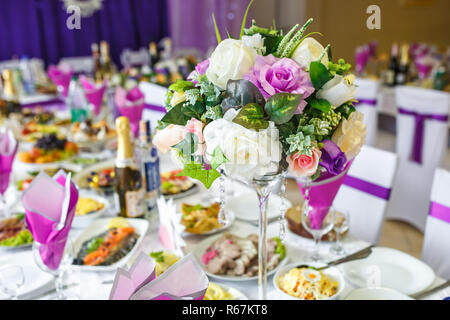 Beautiful flowers on elegant dinner table in wedding day. Decorations served on the festive table in violet background Stock Photo