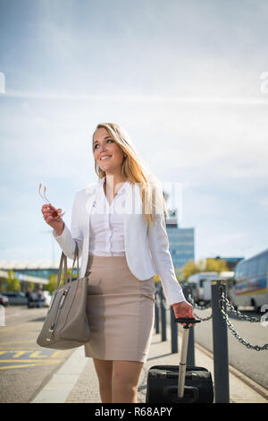 Young female passenger at the airport, walking to he departure terminal from a parking lot (color toned image) Stock Photo