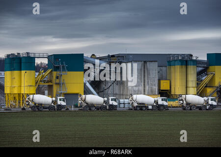 Concrete production plant/factory with  Concrete mixing transport trucks in front of it Stock Photo