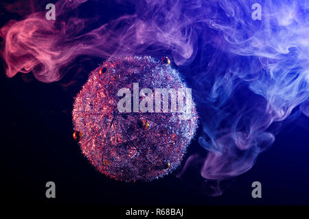 Close up  of a  silver shiny decoration Christmas balls in colored purple-blue smoke, on an isolated black background. Concept of a modern Christmas c Stock Photo