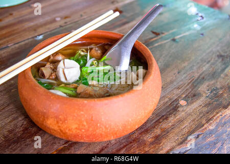 Clay pot rice noodles put on a wooden table Stock Photo