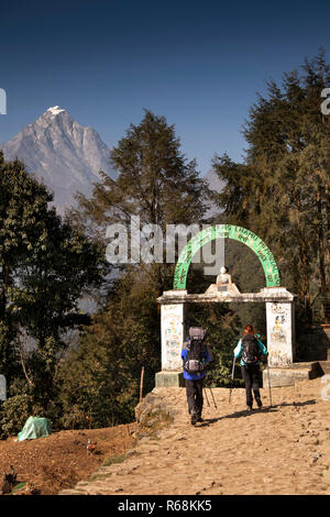 Nepal, Lukla, trekkers passing under National Luminary Pasang Lhamu Memorial gate at northern edge of village, leading to Namche Bazaar, start of Ever Stock Photo