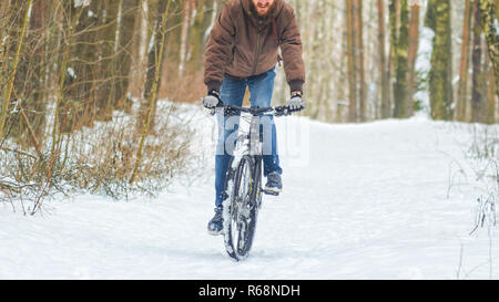 Cyclist Riding the Mountain Bike in Winter Forest. Uphill riding on mtb