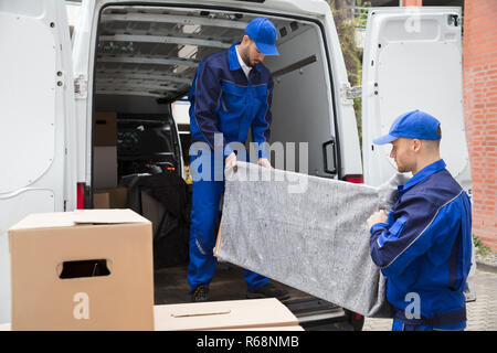 Two Male Worker Unloading Furniture From Truck Stock Photo