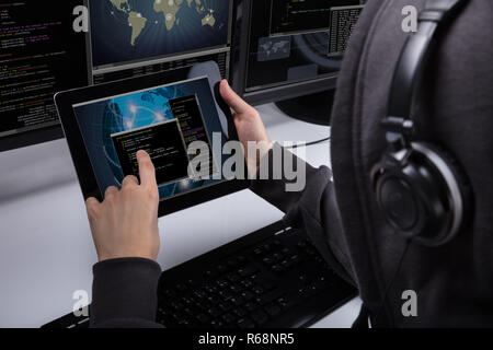 Hacker Using Digital Tablet For Stealing Data Stock Photo