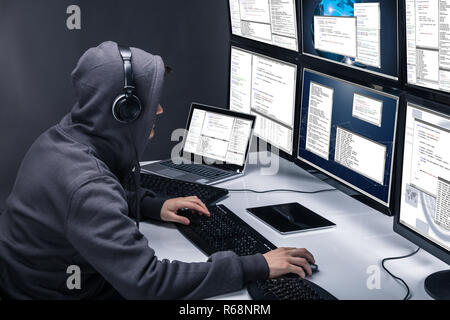 Hacker Using Multiple Computers For Stealing Data Stock Photo