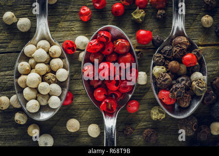 Pepper mix in a spoons on a wooden background Stock Photo