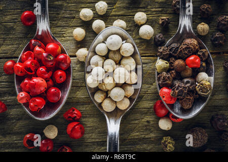 Pepper mix in a spoons on a wooden background Stock Photo