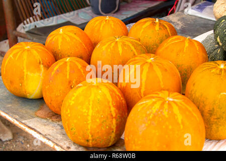 Many orange cantaloupe are on the table.