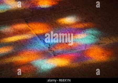Sun light streaming through the stained glass window of a church and coloring the old stone floor Stock Photo