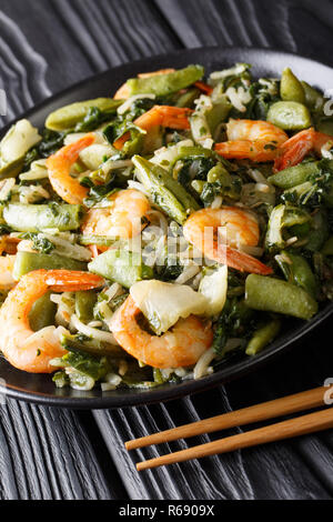 Stir fry of shrimp with spinach, soy sprouts, pea pods and  pak choi close-up on a plate. vertical Stock Photo