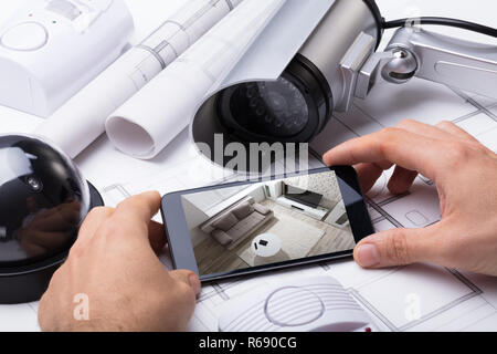 Person Hand Using Home Security System On Mobilephone Stock Photo