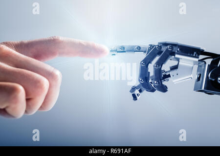 Businessperson's Finger Touching Robotic Finger Stock Photo