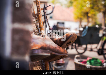 Worn brown leather shoes with holes in the soles, hanging on old vintage fence with the laces tied Stock Photo